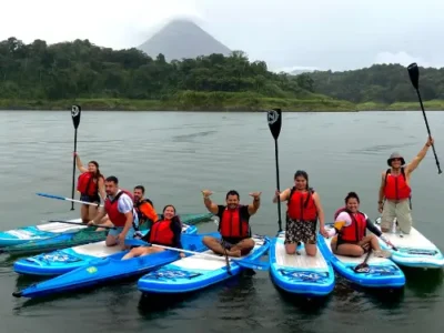 Family paddleboarding on the calm waters of Arenal Lake.