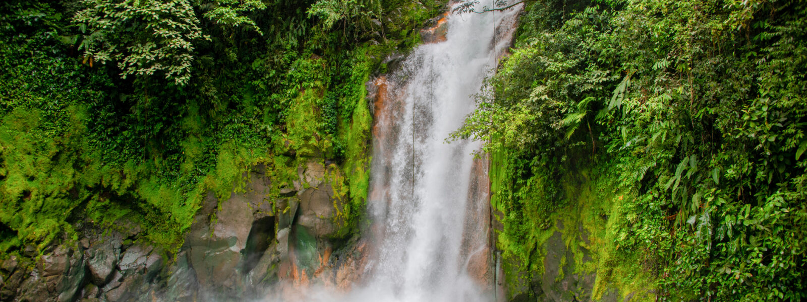 Rio Celeste waterfall, water pours from the mountainside into a stunning, turquoise pool.